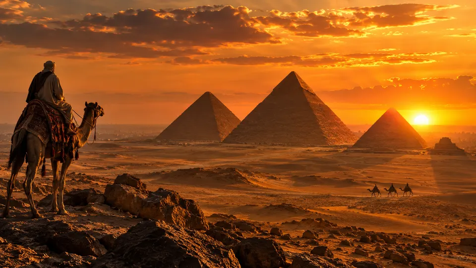 Camel rider looking over the Giza pyramids at sunset